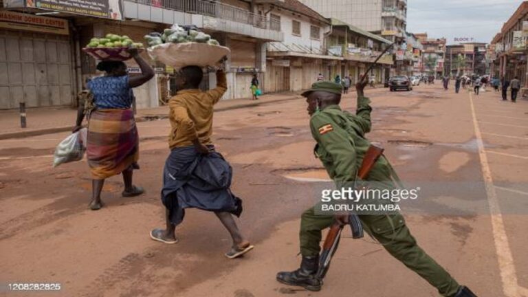 A police officer beats a female orange vendor on a street in Kampala, Uganda, on March 26, 2020, after Ugandan President Yoweri Museveni directed the public to stay home for 32 days starting March 22, 2020 to curb the spread of the COVID-19 coronavirus. - Ugandan authorities have identified 14 confirmed cases of the COVID-19 coronavirus in the country. All borders have been closed except for limited goods and authorised emergency flights. (Photo by Badru KATUMBA / AFP) (Photo by BADRU KATUMBA/AFP via Getty Images)