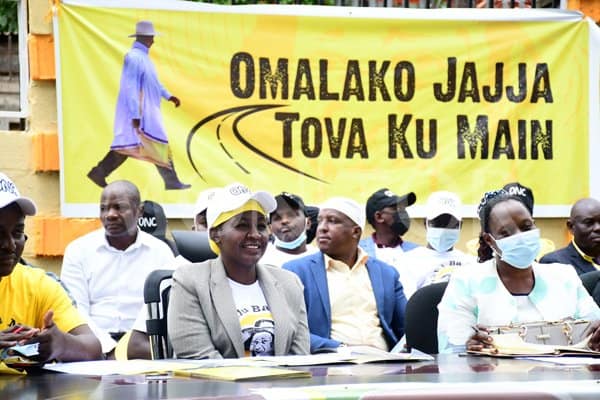 Leaders sit in front of a banner showing the popular campaign slogan claimed by Frank Gashumba